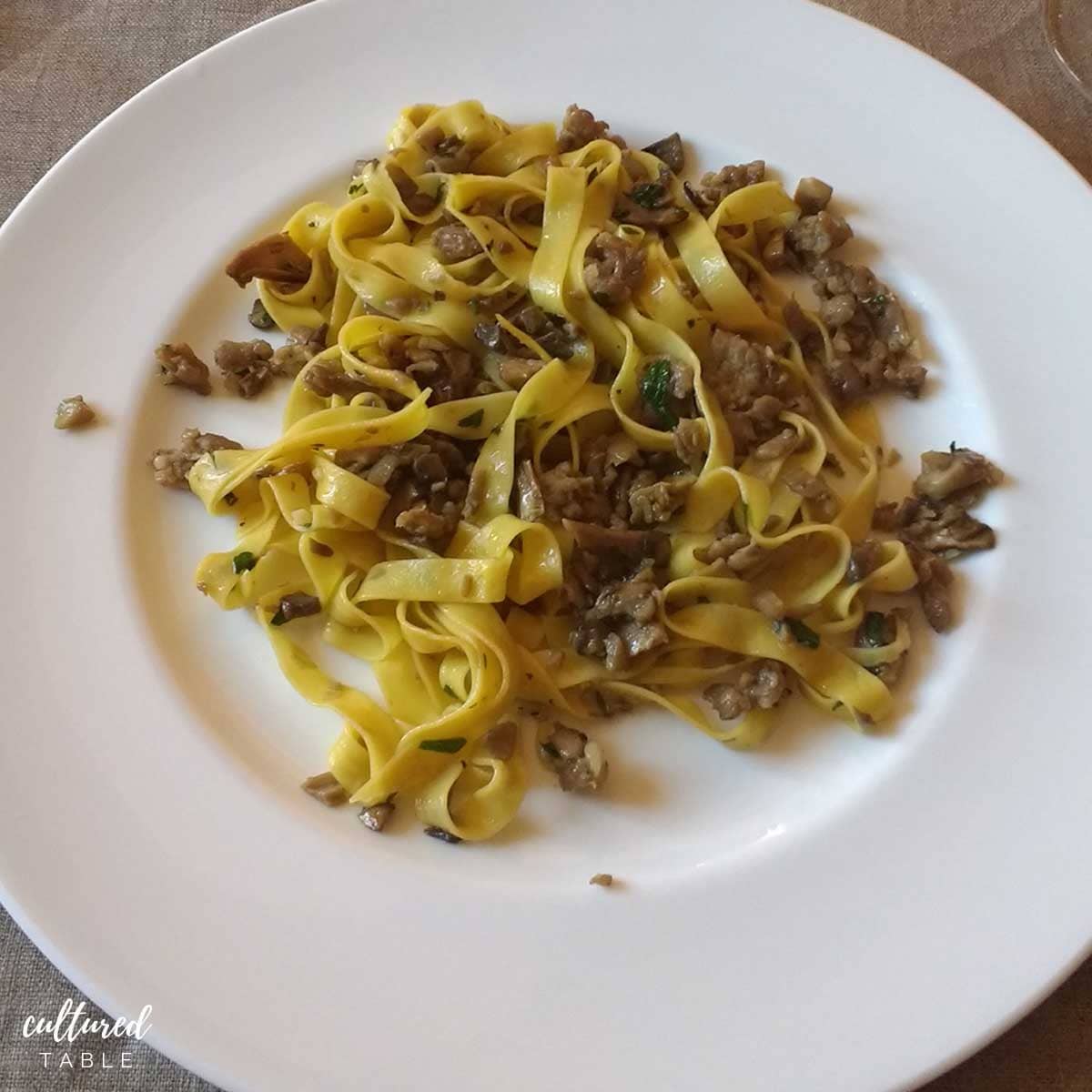 mushroom sausage pasta on a white plate.